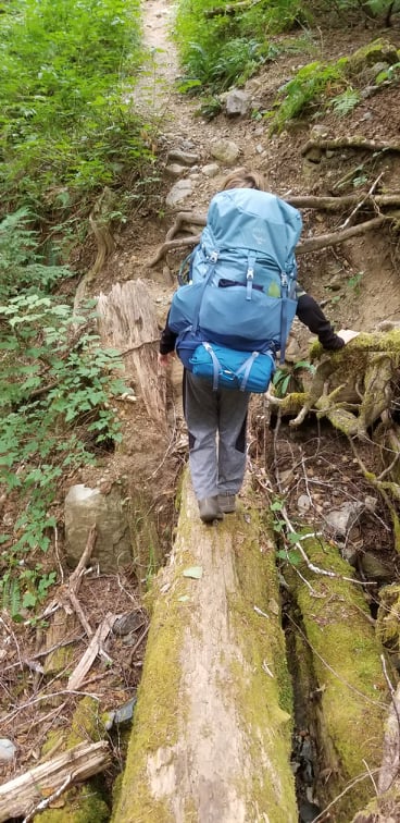 Simon balancing on a log on Della Falls Trail